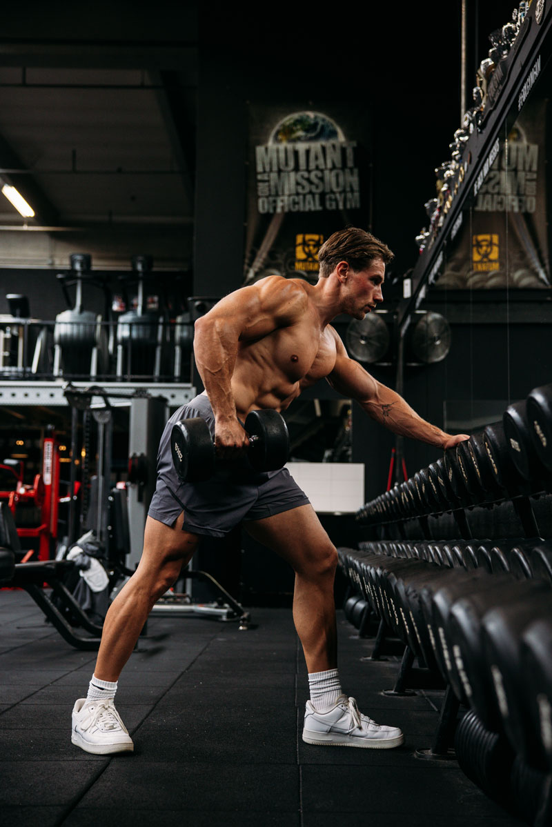 The coach is exercising with weights in the gym.